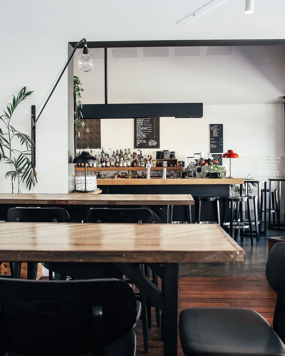Café bar with a long communal table and bottles on the back shelf